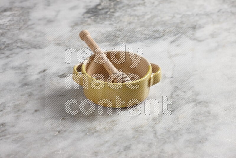 Multicolored pottery bowl with wooden honey dipper in it on grey marble background