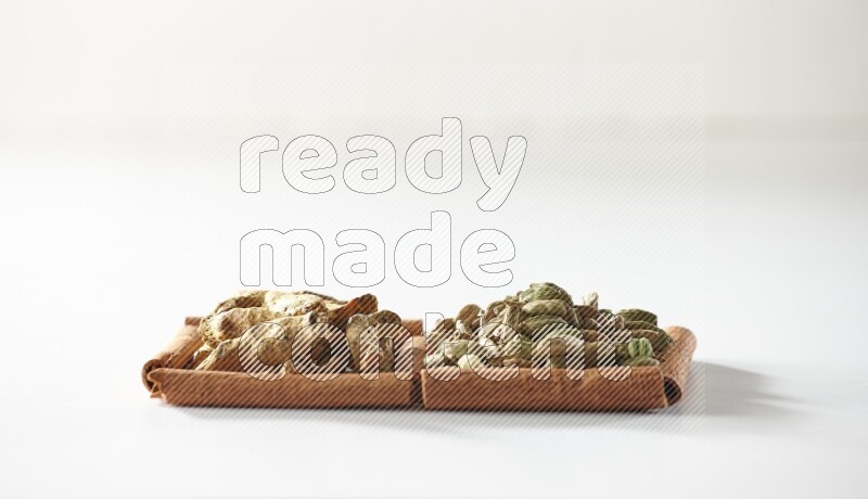 2 squares of cinnamon sticks full of cardamom and turmeric fingers on white flooring