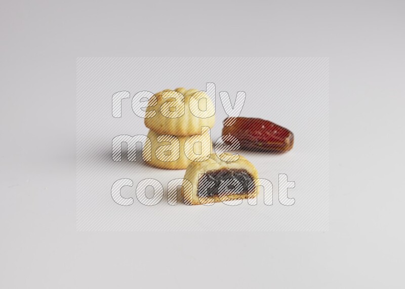 Three Pieces of Maamoul filled with date one of them is cut direct on white background