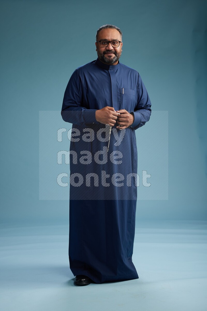 Saudi Man without shimag Standing Interacting with the camera on blue background
