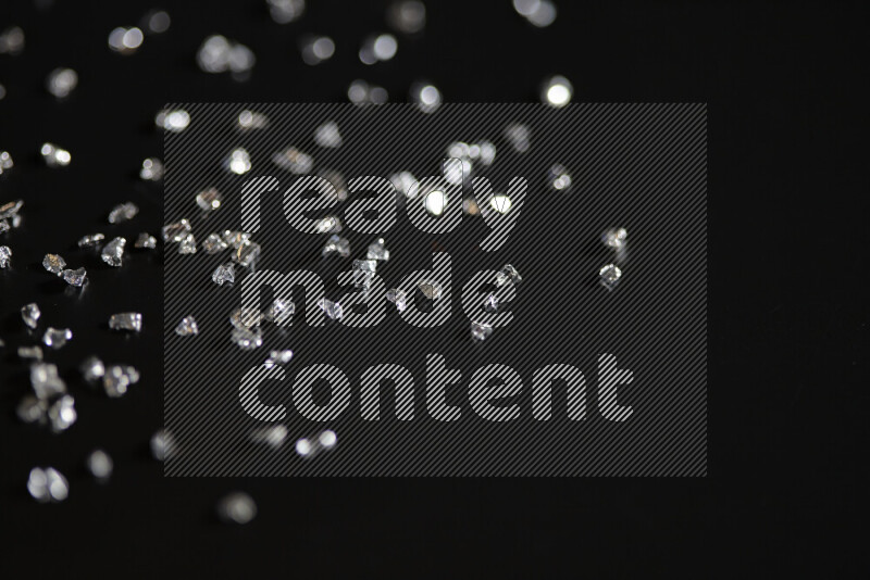 Silver shimmering fragments of glass scattered on a black background