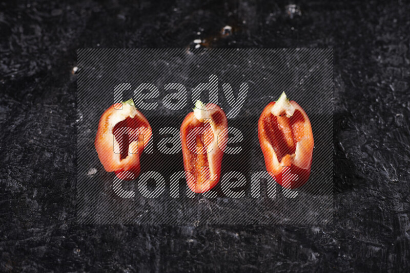 Red bell pepper slices on black background
