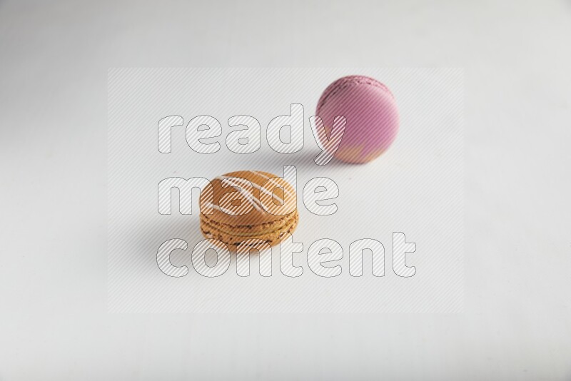 45º Shot of of two assorted Brown Irish Cream, and Purple Strawberry macarons on white background