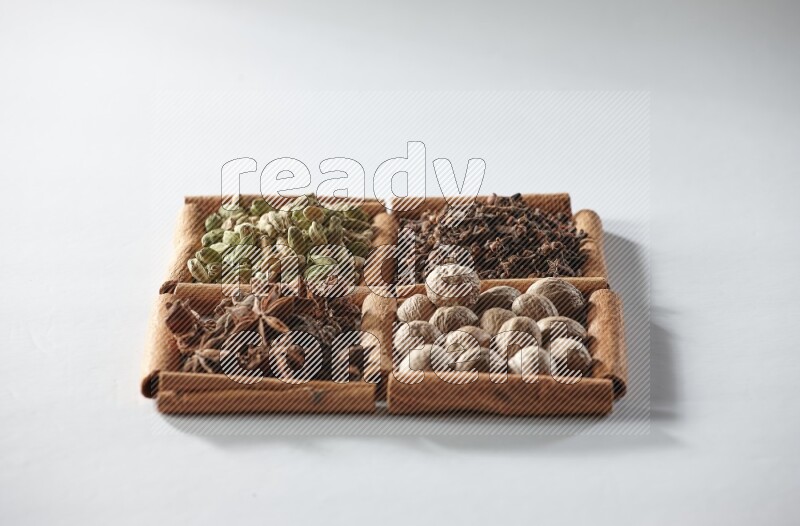 4 squares of cinnamon sticks full of cardamom, star anise, cloves and nutmeg on white flooring