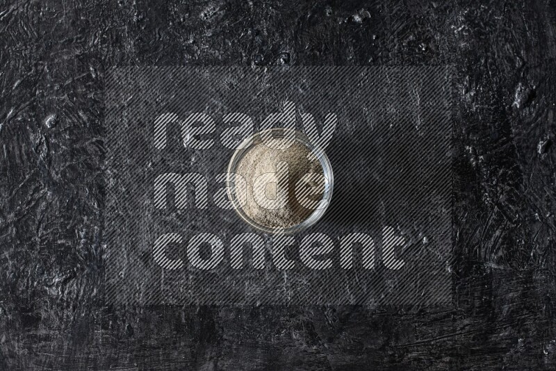 وعاء زجاجي مملوء بمسحوق الفلفل الأبيض على أرضية سوداء