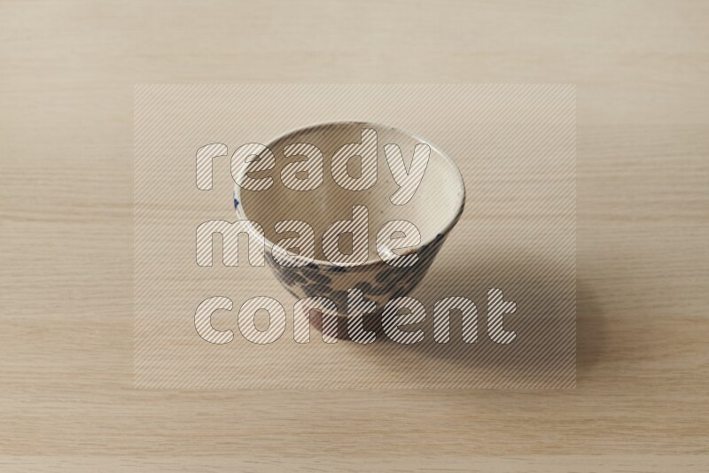 A decorative pottery bowl on light wooden background