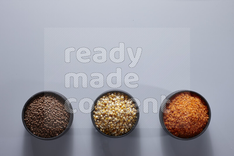 Legumes in pottery bowls on light grey background