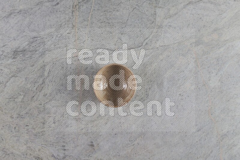 A small beige pottery bowl on grey marble background
