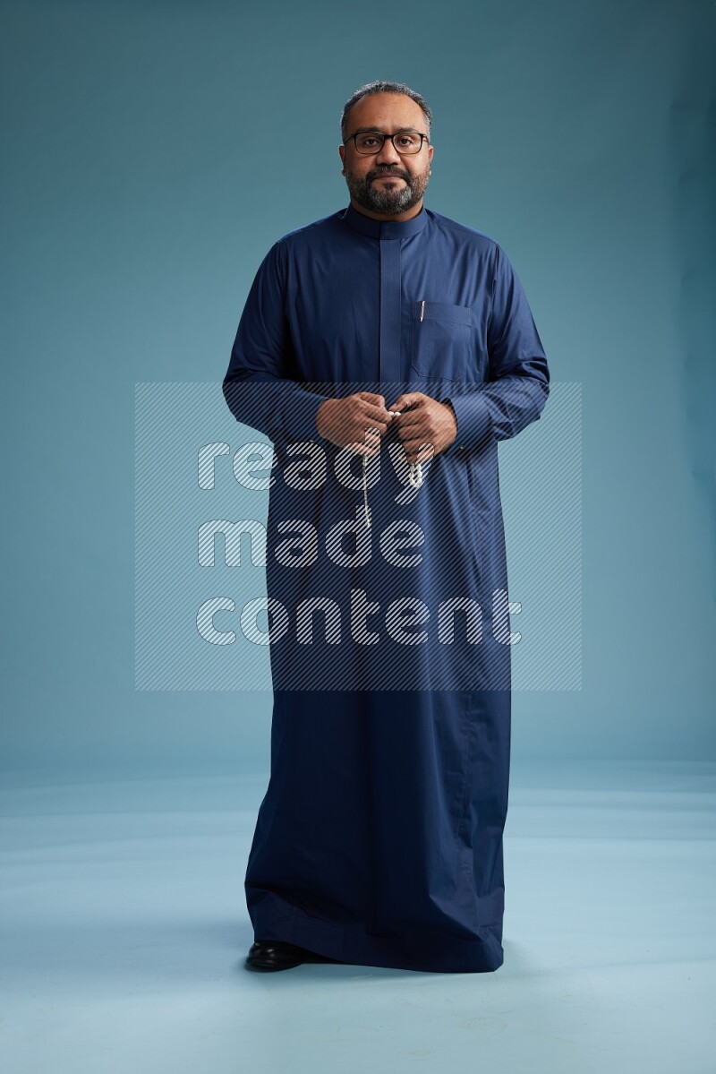 Saudi Man without shimag Standing Interacting with the camera on blue background