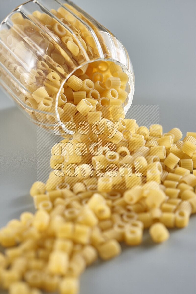 Flipped jar full of raw pasta on light blue background