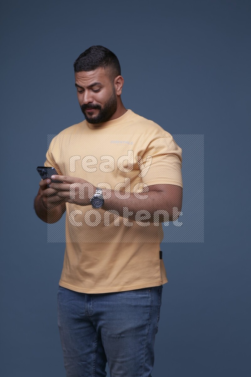 A man Texting on his phone in Blue Background wearing Orange T-shirt