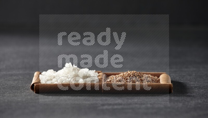 2 squares of cinnamon sticks full of mustard seeds and white salt on black flooring