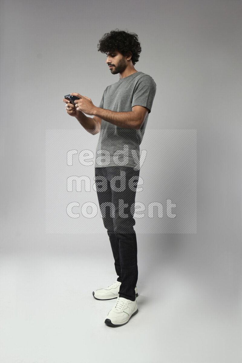 A man wearing casual standing and gaming on the phone on white background