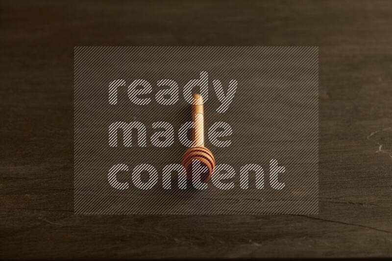 Wooden honey dipper on black slate background