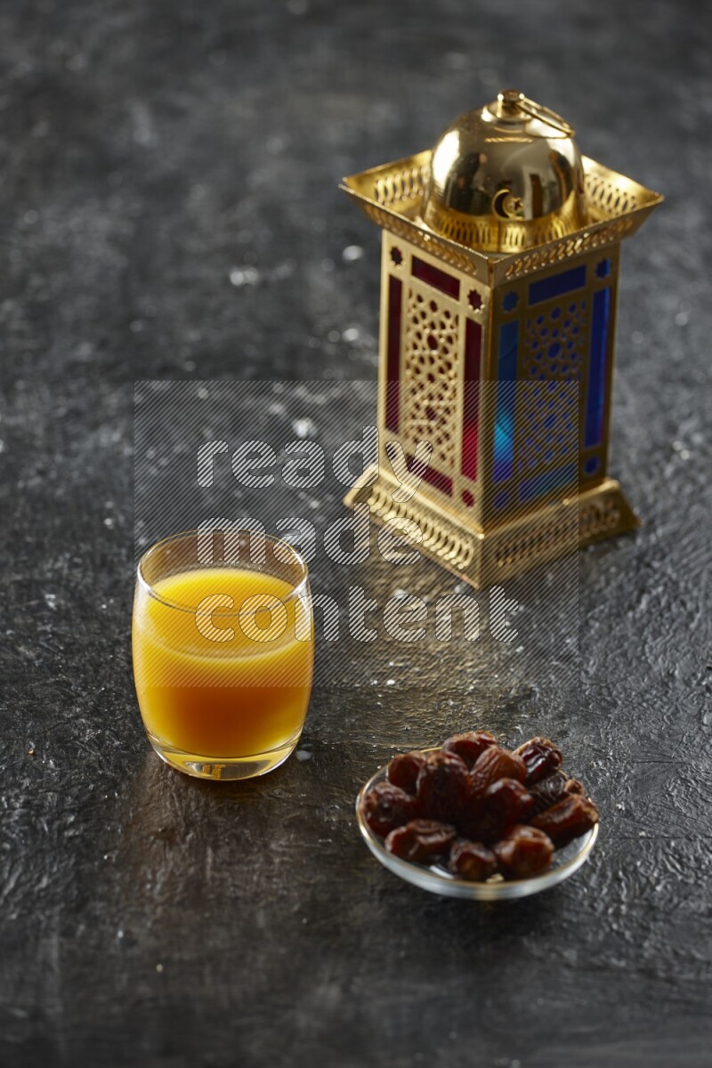 A golden lantern with different drinks, dates, nuts, prayer beads and quran on textured black background