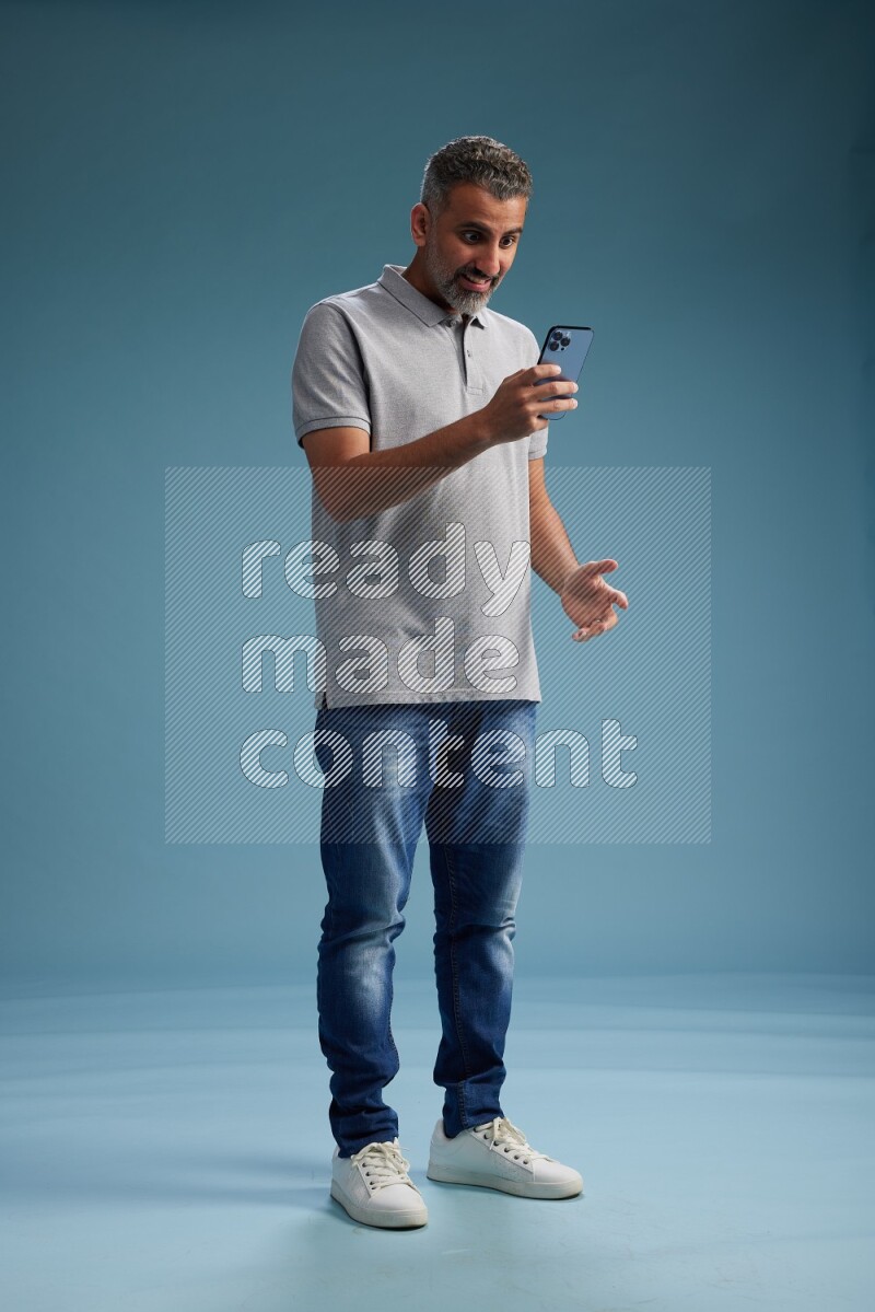 Man Standing texting on phone on blue background