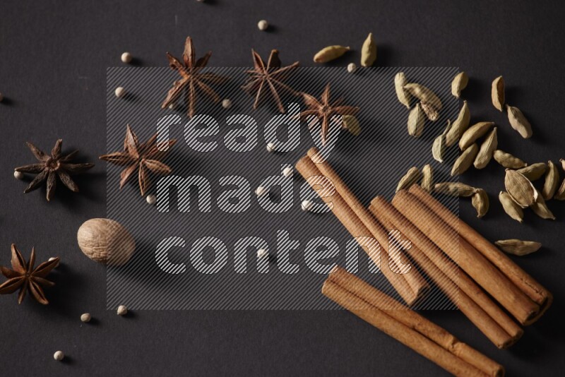 Cinnamon sticks, cardamom, star anise, nutmeg and white peppers on a black background