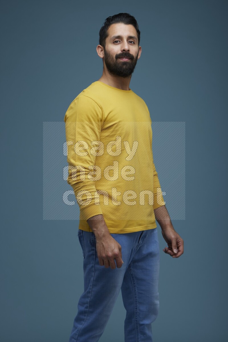 Man posing in a blue background wearing a yellow shirt