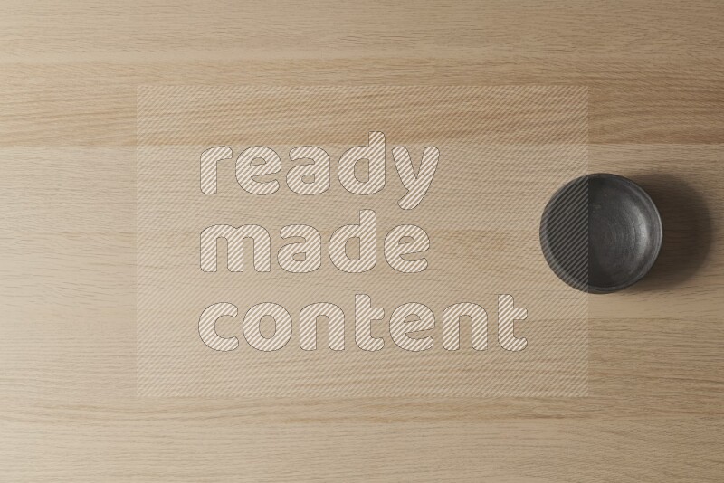 A black pottery bowl on light wooden background