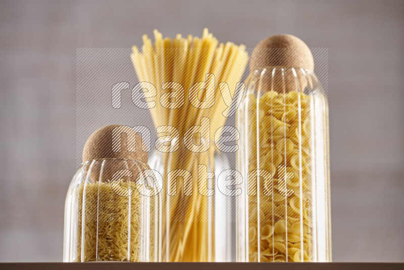 Raw pasta in glass jars on beige background