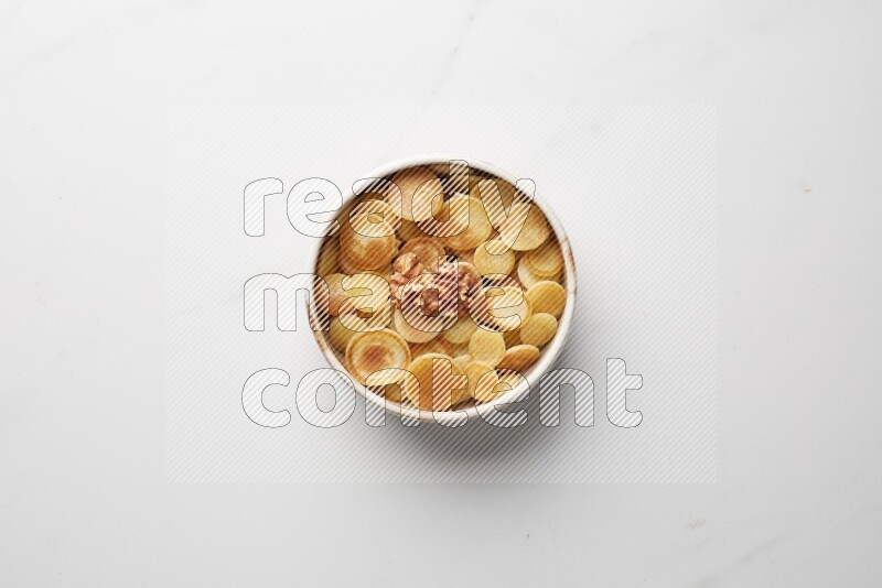 Top-view shot of walnut cereal pancakes in a round bowl on white background