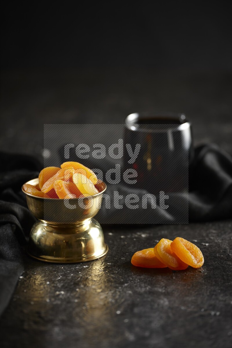 Dried fruits in a metal bowl with tamarind and a napkin in a dark setup
