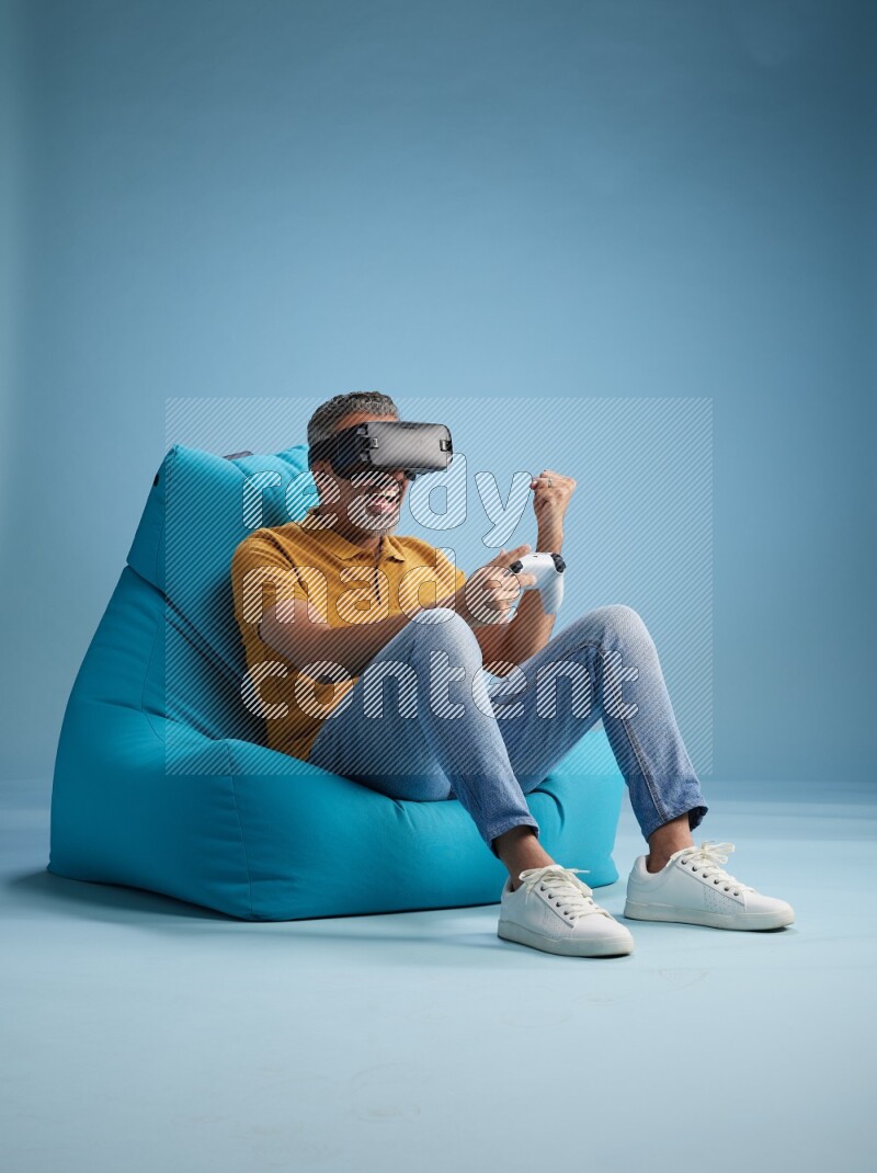 A man sitting on a blue beanbag and gaming with VR