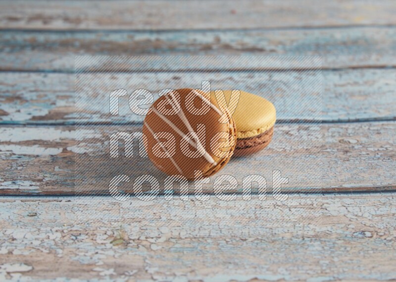 45º Shot of of two assorted Brown Irish Cream, and Yellow, and Brown Chai Latte macarons  on light blue background