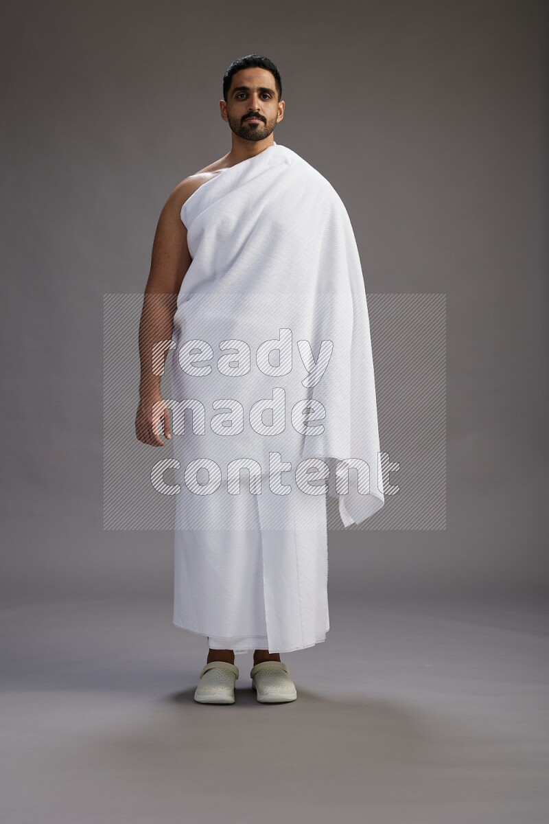 A man wearing Ehram Standing Interacting with the camera on gray background