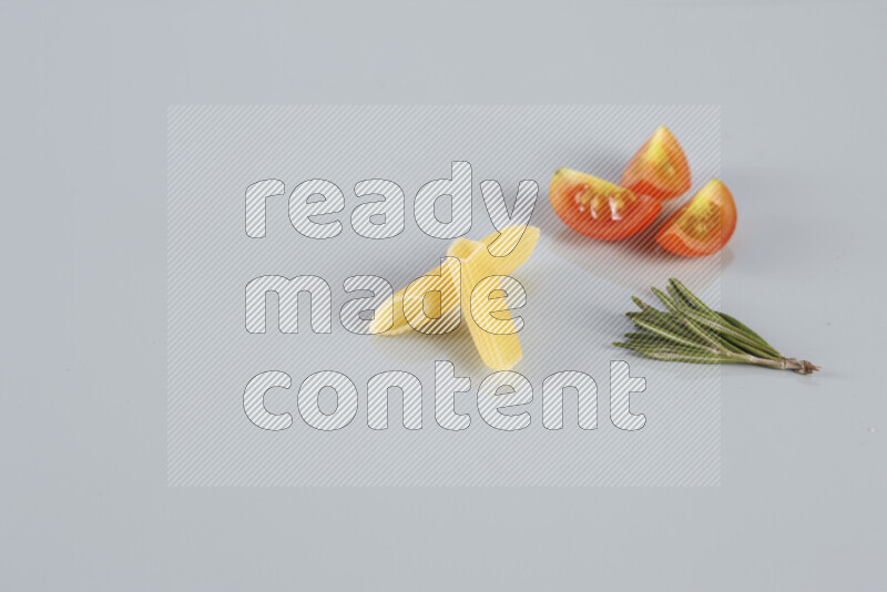 Raw pasta with different ingredients such as cherry tomatoes, garlic, onions, red chilis, black pepper, white pepper, bay laurel leaves, rosemary, cardamom and mushrooms on light blue background
