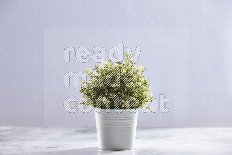 Artificial plant in white pot on grey marble background