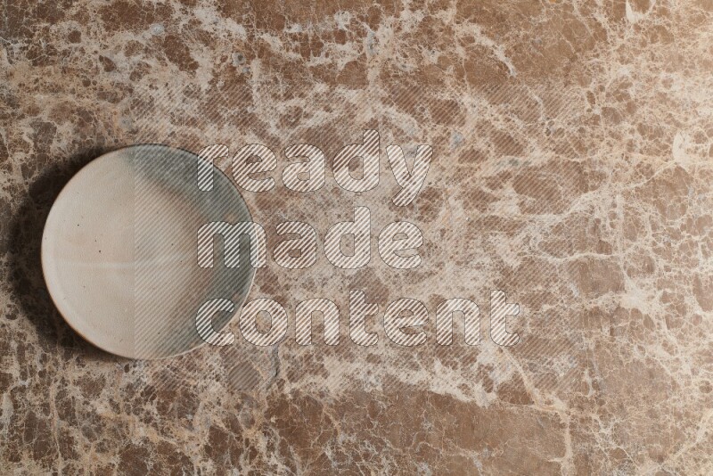 A multicolored pottery plate on beige marble background