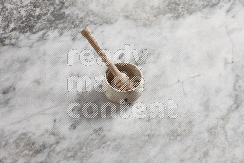 Beige pottery bowl with wooden honey dipper in it on grey marble background