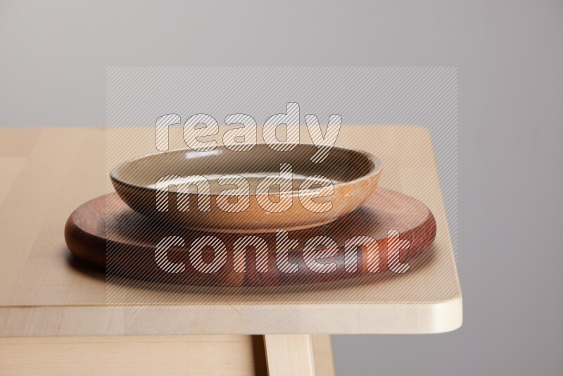 multi-colored pottery Plate placed on a dark colored wooden tray on the edge of wooden table