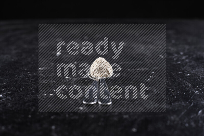 Two metal spoons full of onion powder on black background