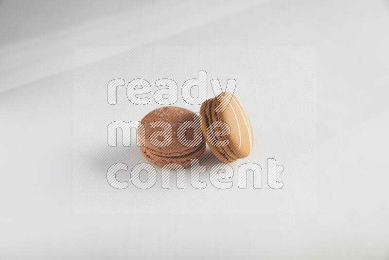 45º Shot of of two assorted Brown Irish Cream, and Brown Hazelnuts macarons on white background