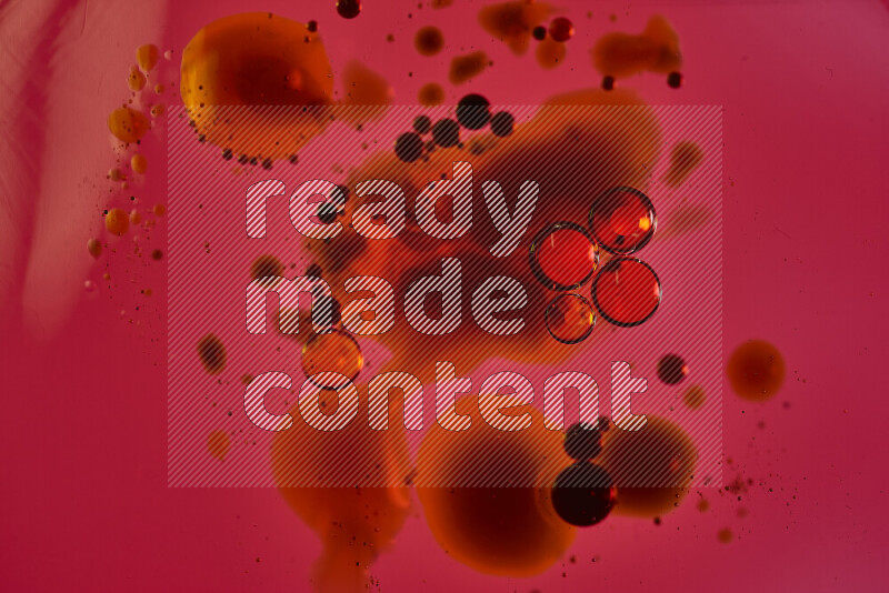 لقطات مقربة لقطرات ألوان مائية حمراء وزرقاء وصفراء على سطح الزيت على خلفية حمراء