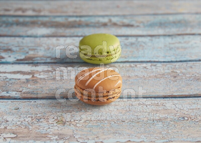 45º Shot of of two assorted Brown Irish Cream, and Green Pistachio macarons  on light blue background