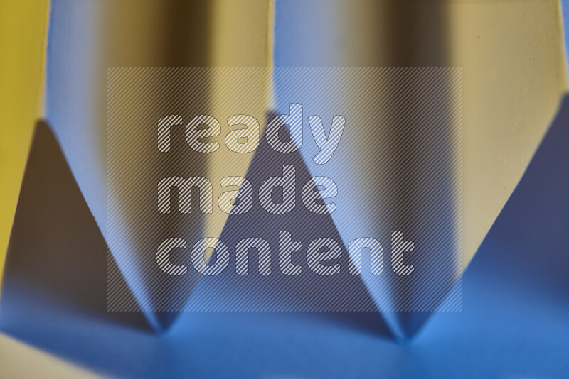 A close-up abstract image showing sharp geometric paper folds in blue gradients and warm tones