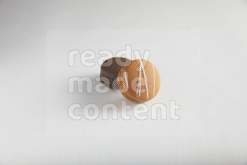 45º Shot of of two assorted Brown Irish Cream, and Brown Dark Chocolate macarons on white background