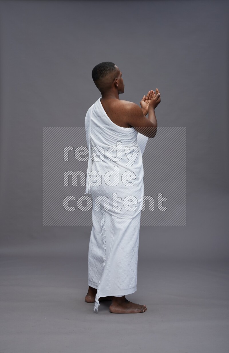 A man wearing Ehram Standing dua'a on gray background