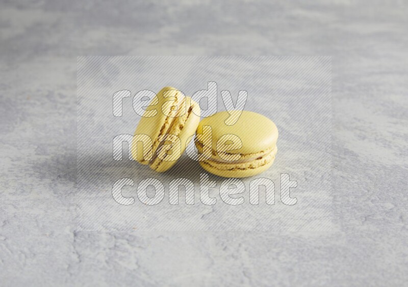 45º Shot of two Yellow Lime macarons  on white  marble background