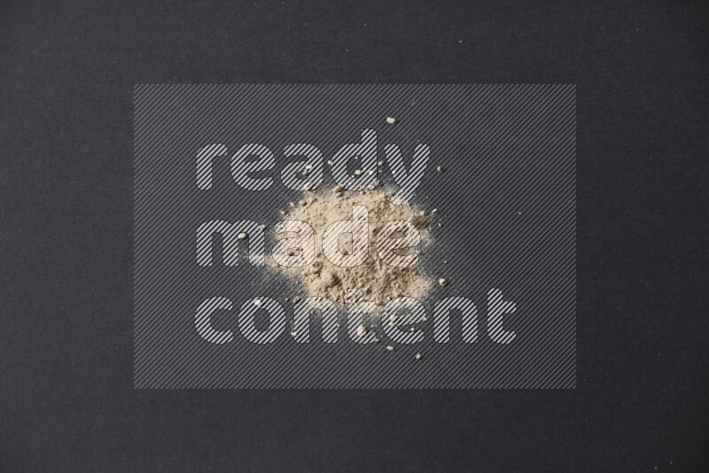 A small pile of garlic powder on a black background