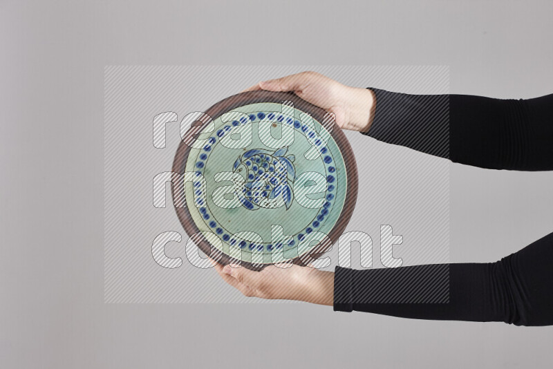 A woman in black abaya holding different pottery essentials in different positions