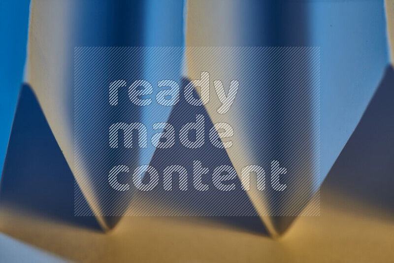 A close-up abstract image showing sharp geometric paper folds in blue gradients and warm tones