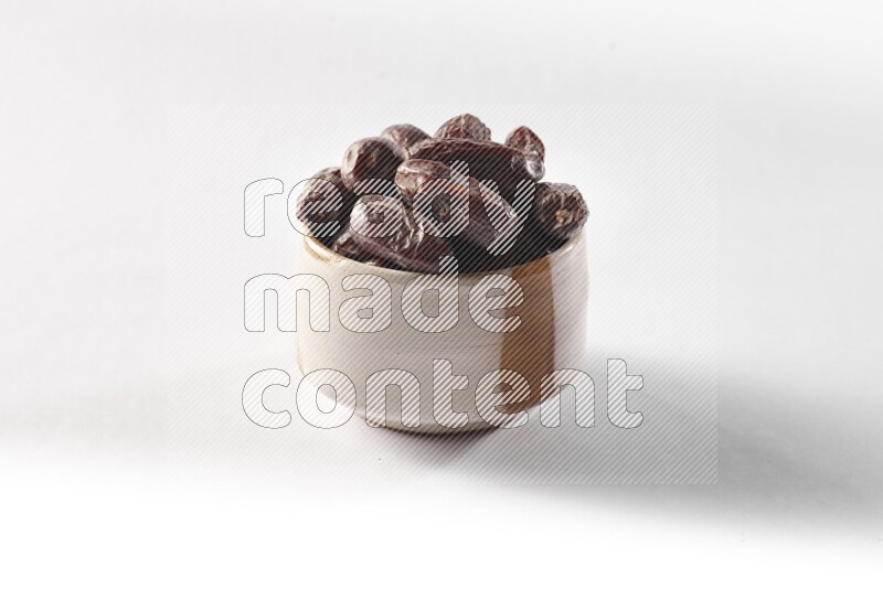 Dates in a beige pottery bowl on white background