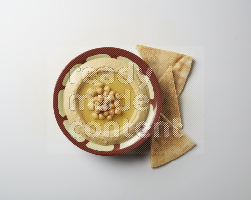 Hummus in a traditional plate garnished with roasted chickpeas  on a white background