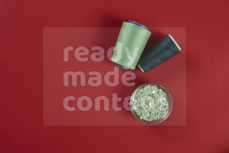 مجموعة من أدوات الخياطة والتفصيل خضراء وحمراء اللون على خلفية حمراء