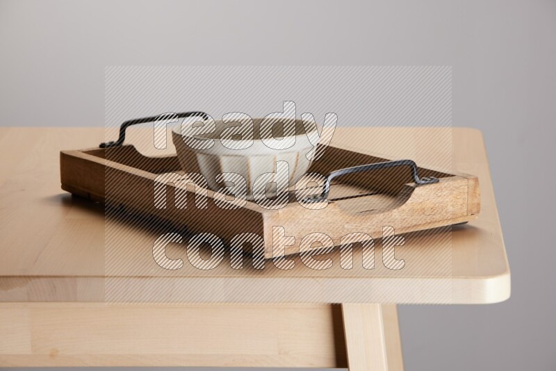 off white bowl on a light colored rectangular wooden tray with handles