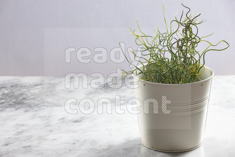 Green artificial plant in white pot on light grey marble background
